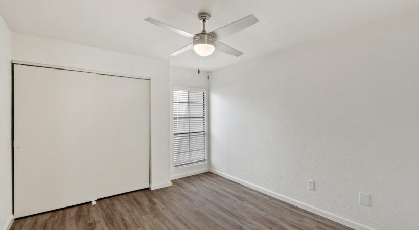 Bedroom with Ceiling Fans and a Large Window at Our Apartments in North Tucson