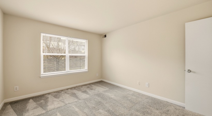 Spacious Bedroom with Carpet Flooring and a Large Window at Our Downtown Leesburg Apartment Homes